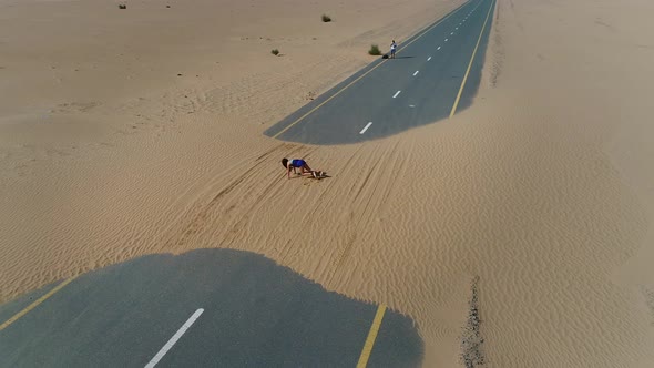 Aerial view of woman starting exercise in road cover by sand on Abu Dhabi, U.A.E