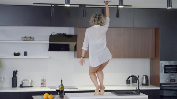 Wide Shot of Sensual Passionate Young Caucasian Woman Dancing on Kitchen Countertop Turning to