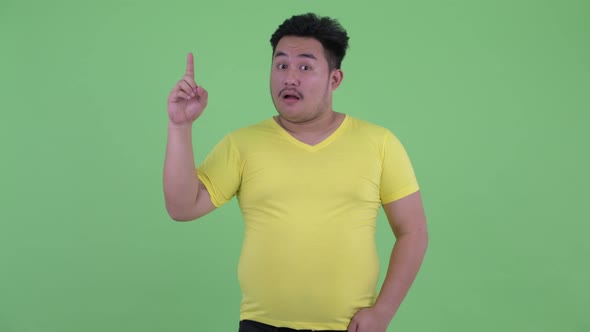 Happy Young Overweight Asian Man Pointing Up