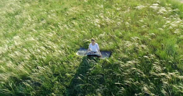 Girl meditates sitting on a beautiful green meadow