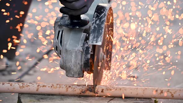 Construction Worker Using Angle Grinder Cutting Metal at Construction Site.