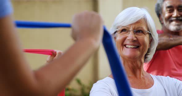 Senior people listening to trainer while exercising with resistance band 4k