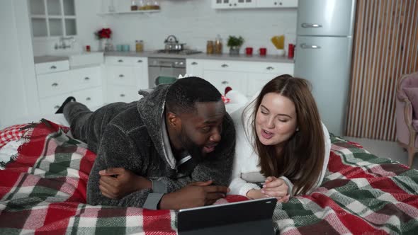 Cheerful Couple Watching Video Clip Lying on Bed