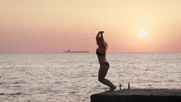 Young Youman Jumping From Sea Pier and Doing Frontflip During Beautiful Sunrise Slow Motion