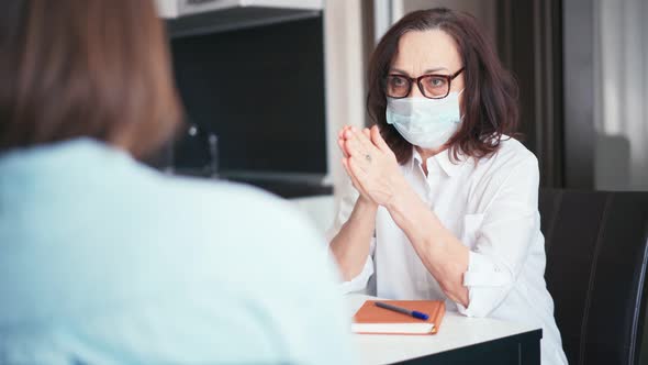 A Mature Woman Doctor Wearing Medical Face Mask Consulting a Patient