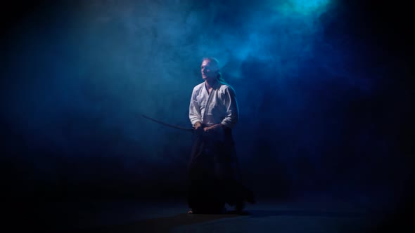 Aikido Master Technique Demonstration with Japanese Sword Katana on Blue Smoke Background