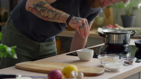 Bearded Man Crushing Spices with Mortar and Pestle