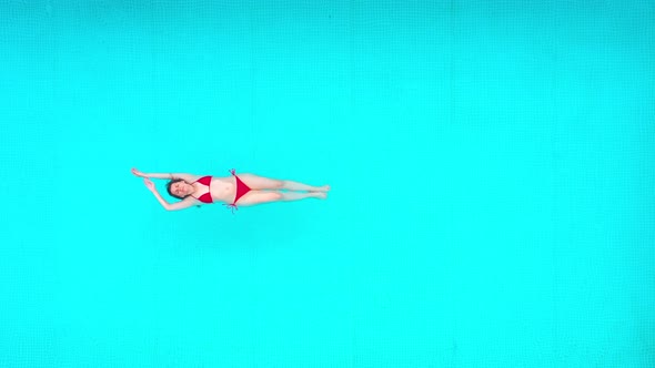 View From the Top As a Woman in a Red Swimsuit Lying on Her Back in the Pool