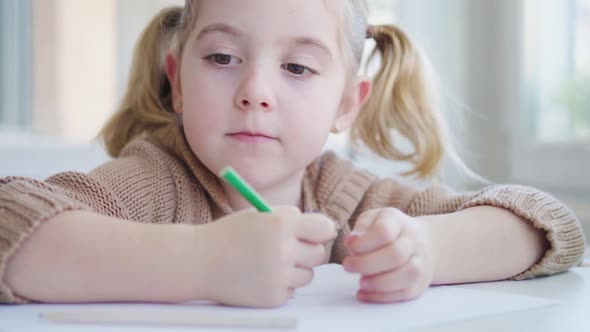 Child with paper and pencil sitting on chair