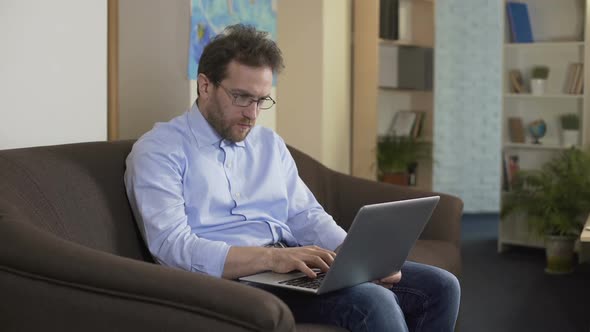 Thoughtful Male Scientist Typing New Article on Laptop, Freelance Work