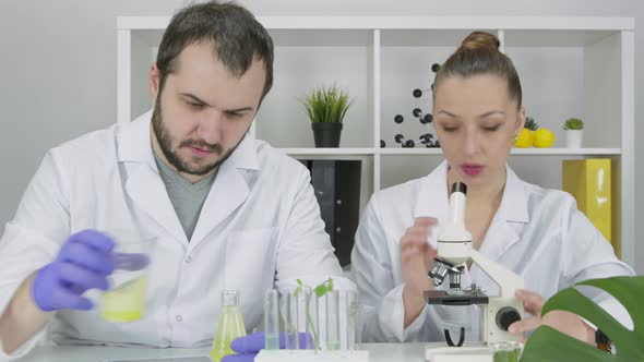 Two Young Researchers in Lab Discussing Results of Research in Biotechnology