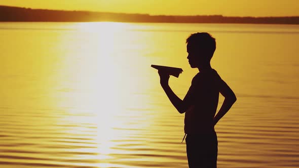 Little Boy is Holding a Paper Airplane in His Hand