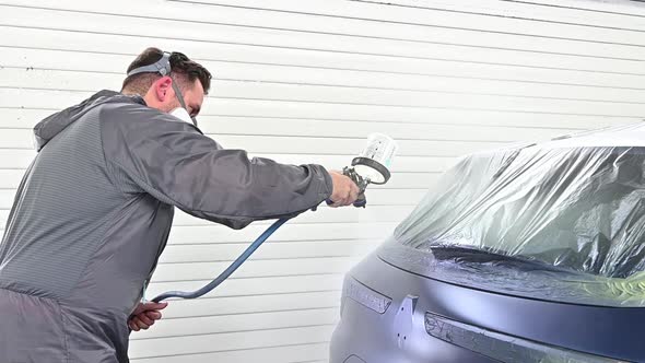 Spraying varnish on trunk of dark blue vehicle, close up view