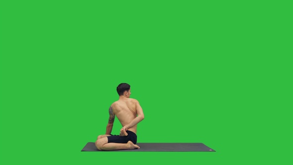 A young strong man doing yoga exercises stretches padmasana