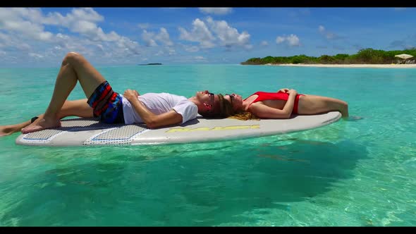 Guy and girl sunbathe on marine coast beach holiday by aqua blue ocean and white sand background of 