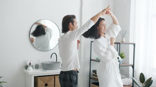 Slow Motion of Happy Couple Man and Woman Dancing in Bathroom Holding Hands