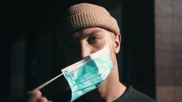 Portrait of a Young Man Taking Off a Protective Mask. Concept of Health and Safety Life, Virus