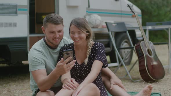 Young family couple talking video calling against motor home RV campervan