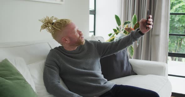 Albino african american man with dreadlocks using smartphone