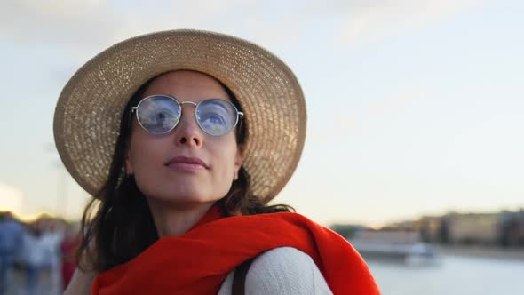 Attractive woman with red scarf on river embankment in european city