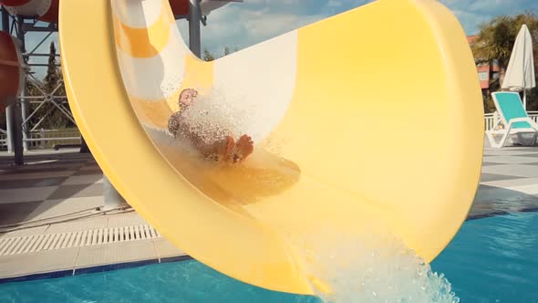 Male On Holiday Resort. Summer Vacation Enjoying On Waterslide. Funny Ride On Water Slide Pool.