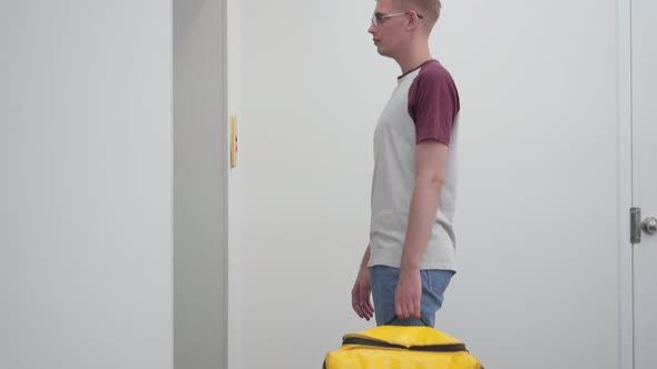 Pedestal Side View Young Courier with Thermal Backpack Waiting for Elevator in House or Business