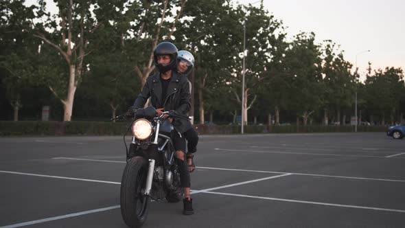 Young Couple in Helmets on Motorcycle in City with Urban Background Dolly Shot