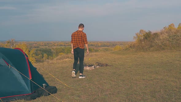 Guy in Orange Shirt Goes Out of Tent and Walks To Bonfire