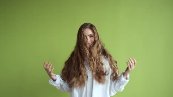 Pretty Girl With Long Hair Stands Near The Wall. Girl Having Fun. She Lifts Her Lush Hair.