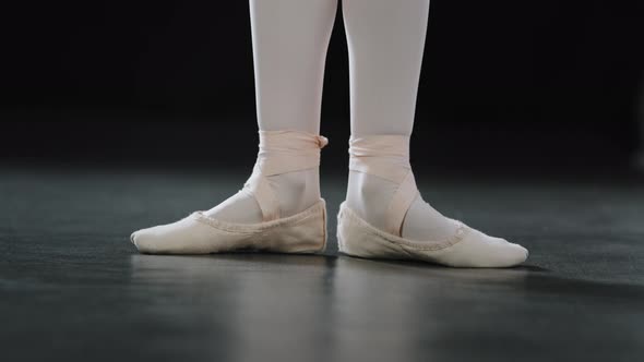 Closeup Female Foot in Pointe Shoes Tying Laces Rise Standing on Floor in Dance Class Stage