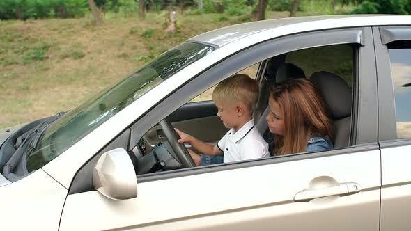 A Little Boy Sits with His Mother at the Wheel of a Car and Turns on the Wipers