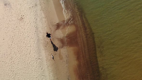 Man with Dog Runs Along the Beach