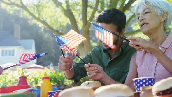 Family holding american flags during meal in the park 4k