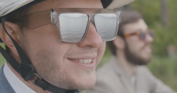 Close-up Face of Confident Young Man in Sunglasses and Helmet Smiling in Slow Motion. Portrait of