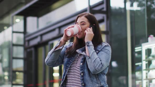 Young Caucasian woman drinking coffee while being on phone