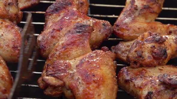 Closeup of the Delicious Chicken Wings Placed on the Grill with Metal Tongs