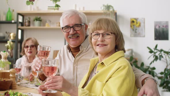 Portrait of Cheerful Senior Couple with Drinks at Home Dinner