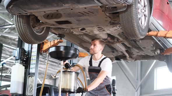 A Young Car Mechanic Changes the Oil in the Engine