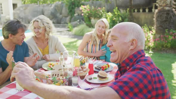 Happy caucasian family having dinner and taking selfie in garden