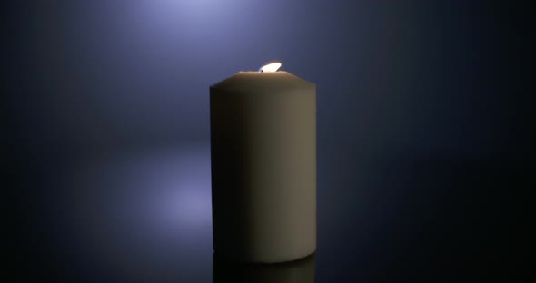 Slow motion close up footage of a white candle on a dark background