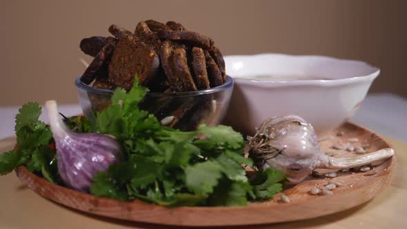 Chicken soup, bread crumbs and fresh greens on a wooden plate