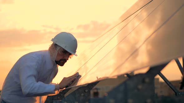 Smooth Surface of a Solar Module Is Getting Polished By a Male Serviceman