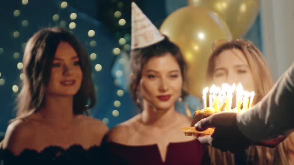 Young Woman Blowing Out Fire on Candles and Making Wish at Party or Celebration