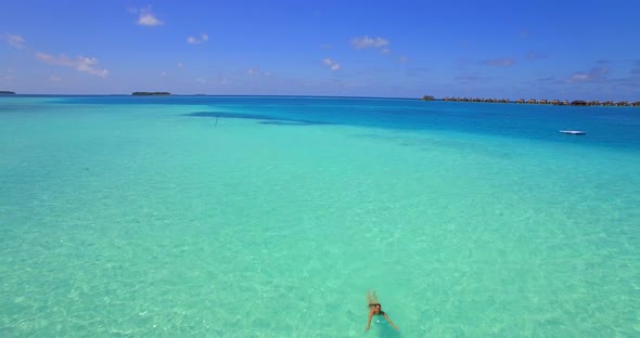 Aerial drone view of a woman floating and swimming on a tropical island.