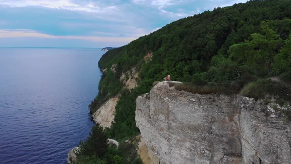 Young Shirtless Man Playing Ukulele on the Cliff Around the Forest and River