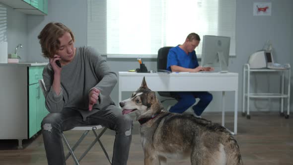 Man Plays with Husky and Talks on Phone in Cabinet of Vet 