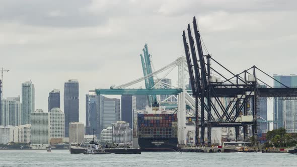 Container Ship Unloading in Miami Port and Miami Downtown at Cloudy Day