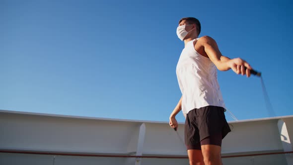 Handsome Young Athletic Man in White Mask and Tshirt Jump Rope Outdoor