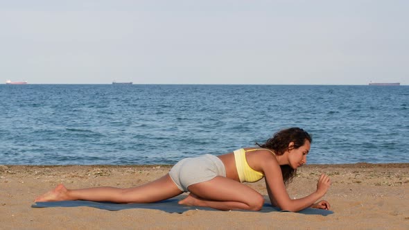 Beautiful tanned young woman sitting in a meditation pose on the beach. Goods for health.