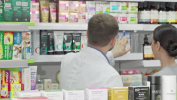 Male Pharmacist and His Female Customer Discussing Products on Sale